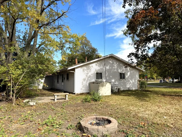 a view of a white house next to a yard with a large tree