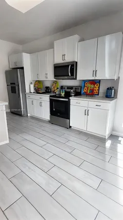a kitchen with granite countertop a refrigerator and a stove top oven