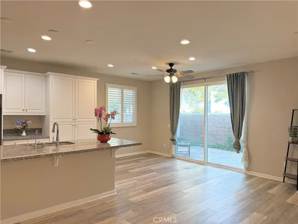 a living room with stainless steel appliances furniture refrigerator and wooden floor