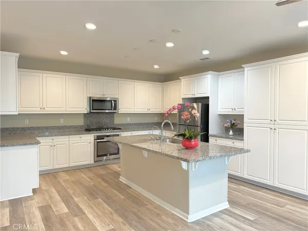 a kitchen with stainless steel appliances granite countertop a refrigerator sink and white cabinets