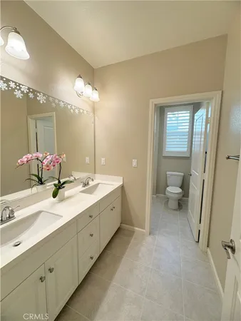 a spacious bathroom with a double vanity sink a mirror and a toilet