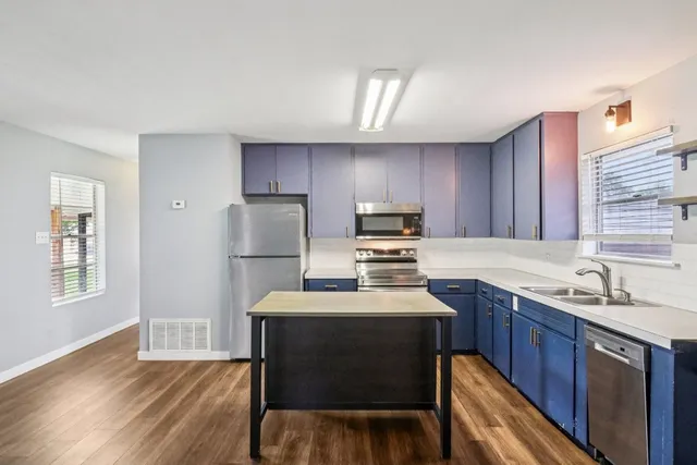 a kitchen with a sink a stove a refrigerator cabinets and wooden floor