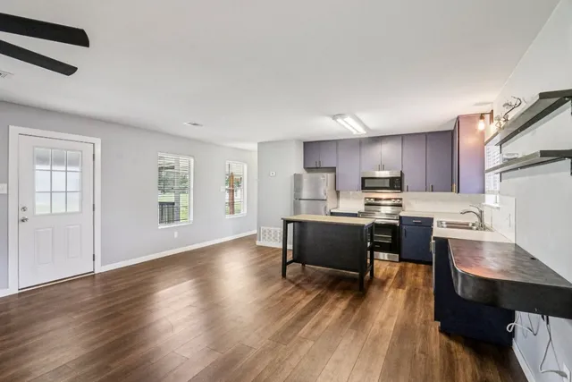 a living room with stainless steel appliances kitchen island granite countertop wooden floor a dining table and chair