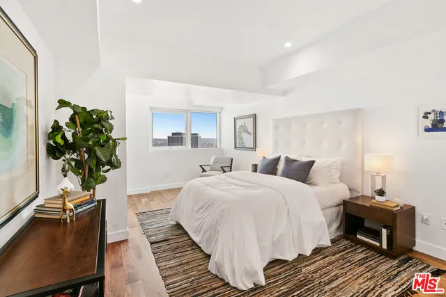 a bedroom with a bed and a potted plant on the dresser