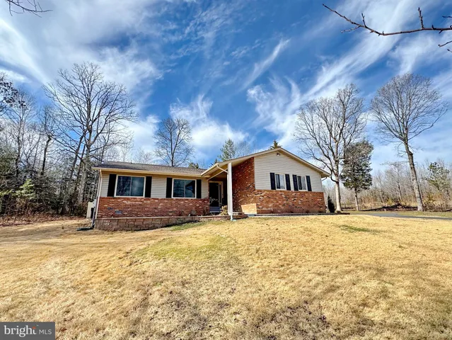 a front view of house with yard and trees in the background