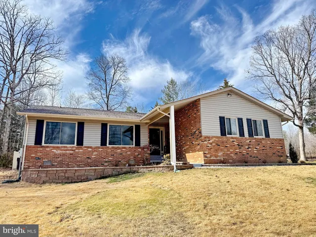 a front view of house with yard and trees in the background
