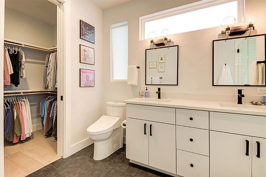 916 East 50th Street, Unit 1 Austin, TX 78751 - Photo 17 of 36 Walk-in closet off of the primary bathroom, which features a bidet toilet, matte black hardware / plumbing fixtures, soft close drawers and quartz countertops.
