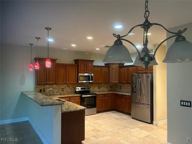 a kitchen with kitchen island granite countertop a sink a counter top space appliances and cabinets