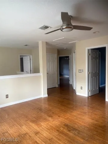 a view of a hallway with wooden floor and a bathroom