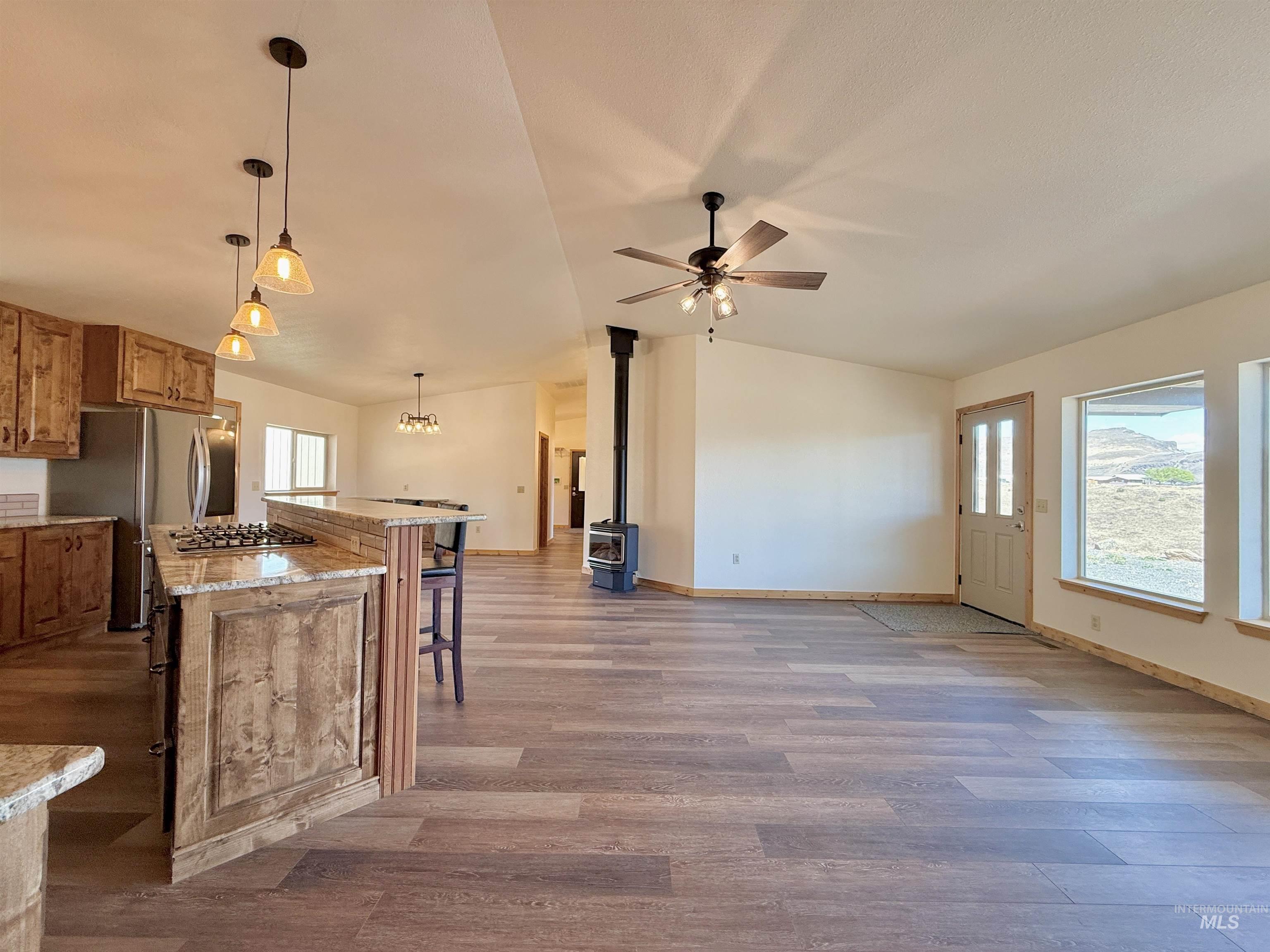 150 Buck Boulevard White Bird, ID 83554 - Photo 11 of 45 Kitchen featuring a center island, wood finished floors, lofted ceiling, a kitchen breakfast bar, and brown cabinets