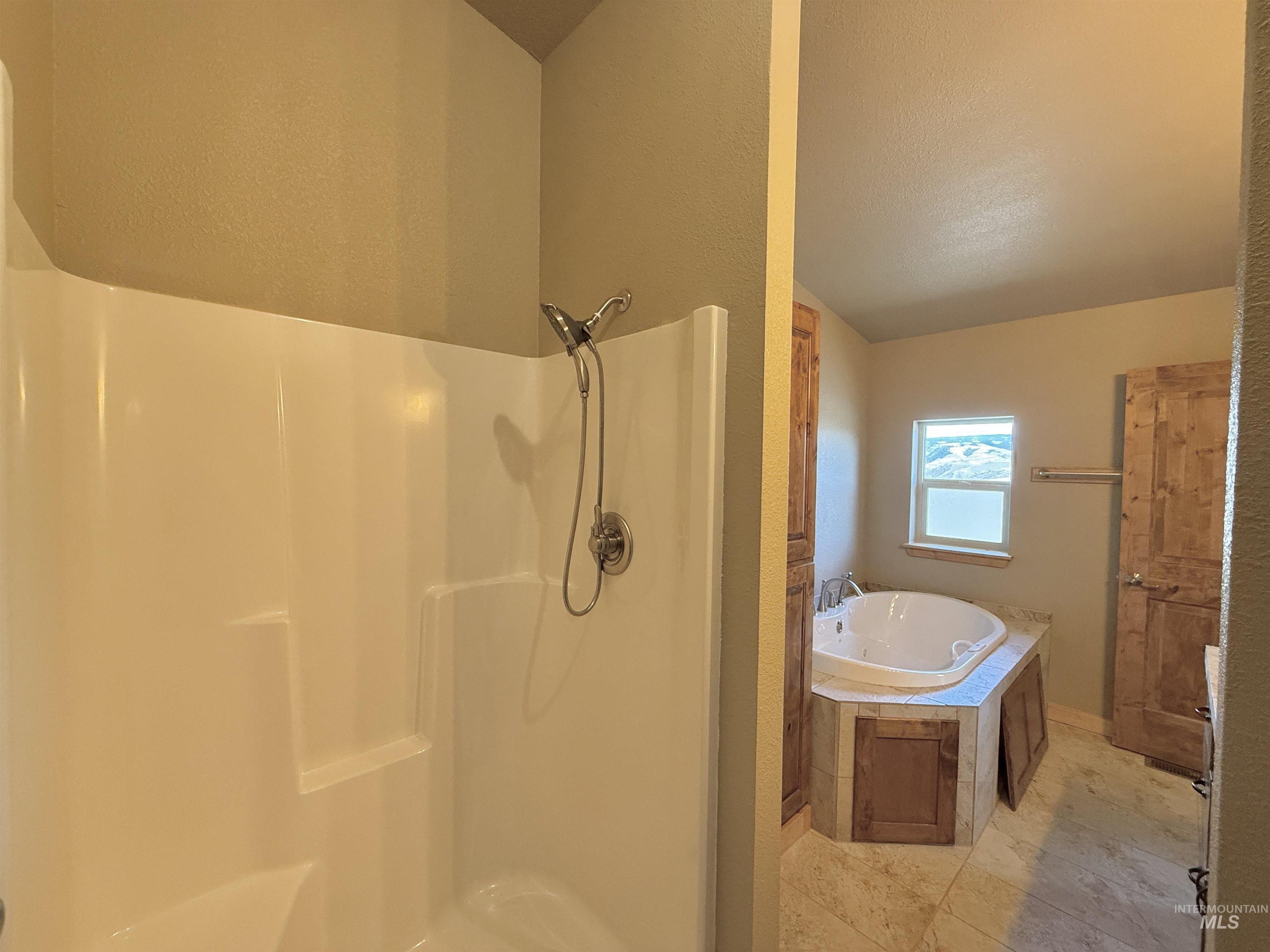 150 Buck Boulevard White Bird, ID 83554 - Photo 21 of 45 Full bathroom with a walk in shower, a garden tub, and a textured ceiling