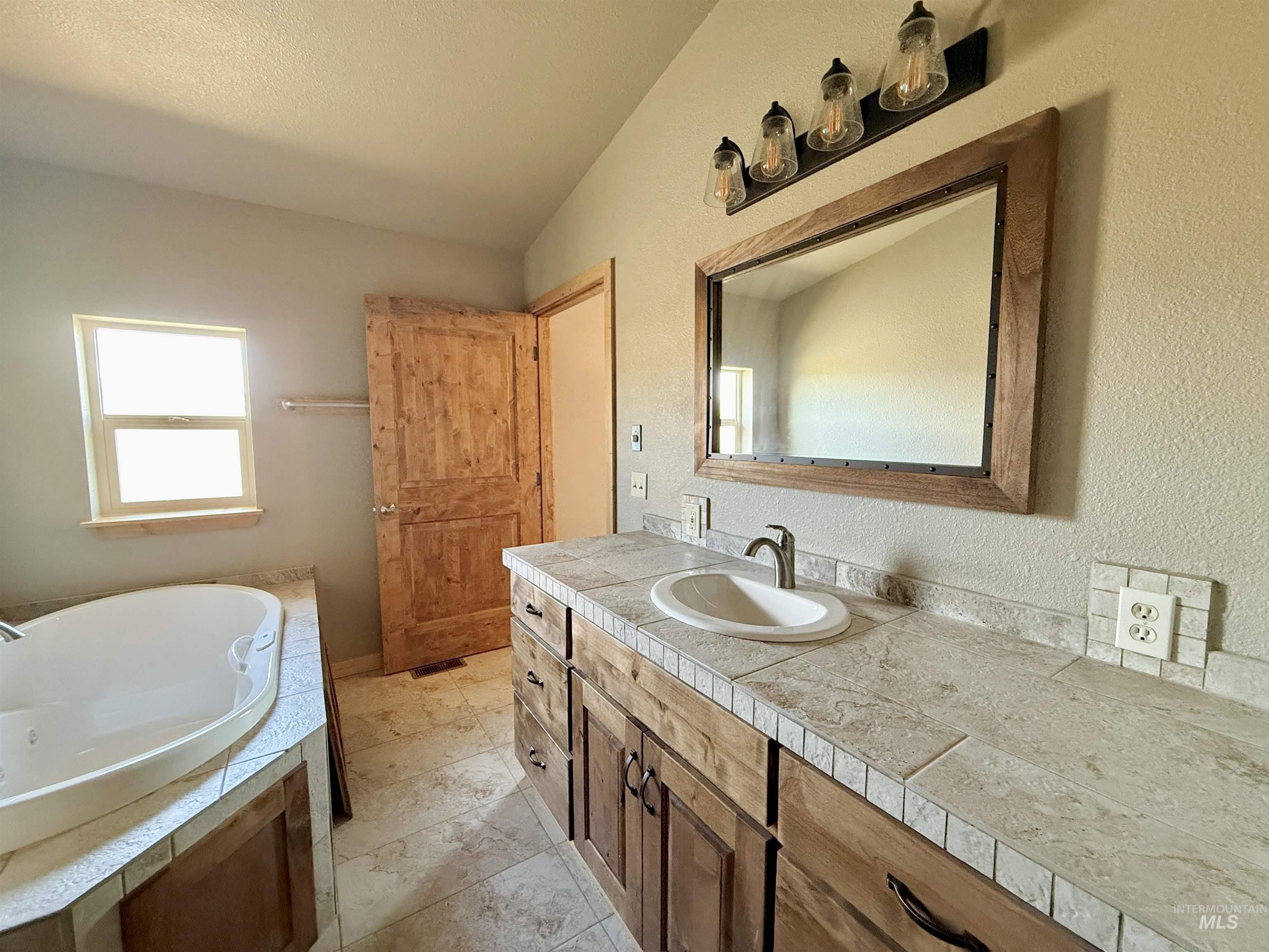 150 Buck Boulevard White Bird, ID 83554 - Photo 22 of 45 Full bath with a tub with jets, vanity, and a textured wall