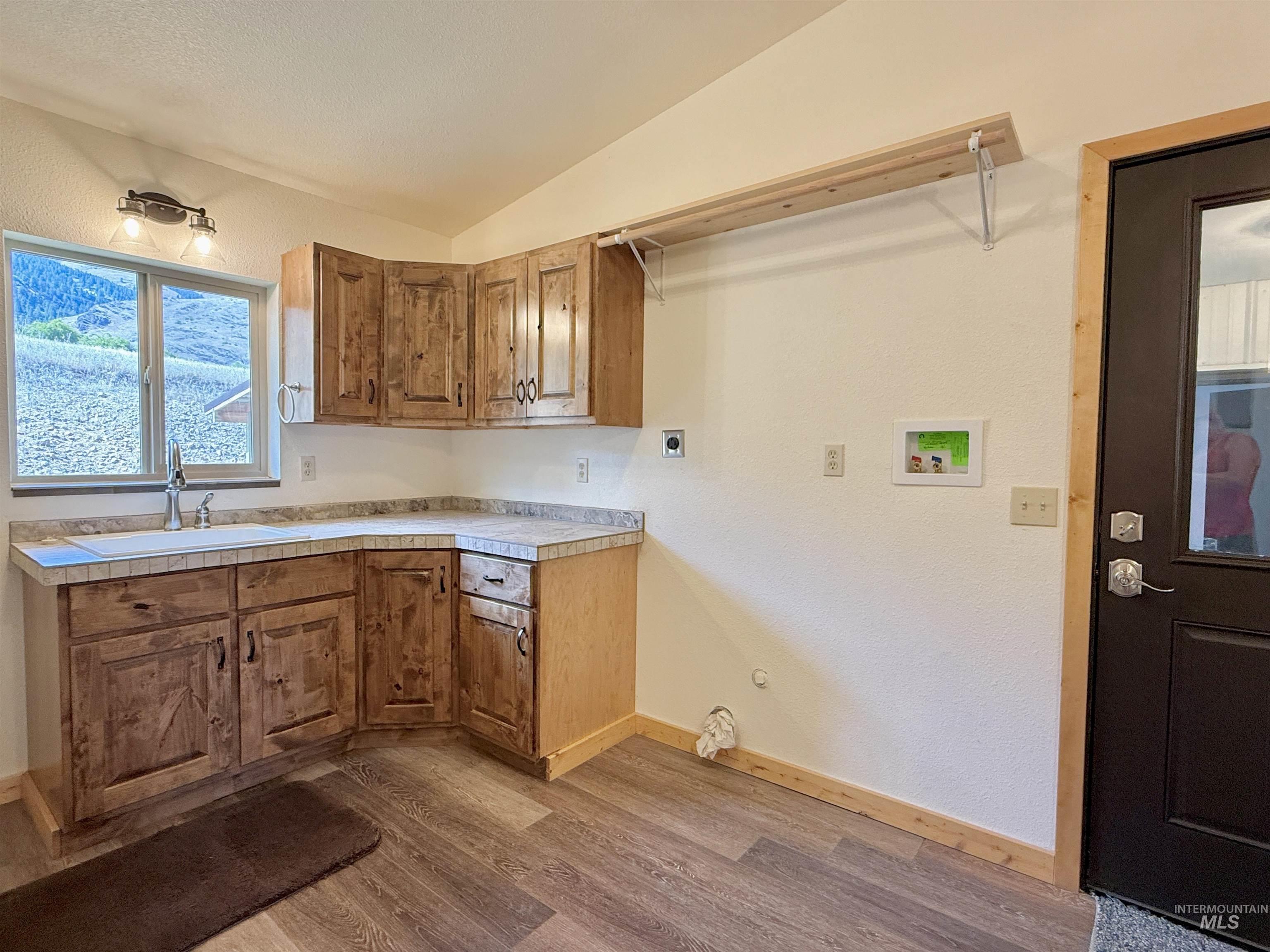 150 Buck Boulevard White Bird, ID 83554 - Photo 24 of 45 Kitchen with brown cabinets, wood finished floors, light countertops, a textured wall, and vaulted ceiling