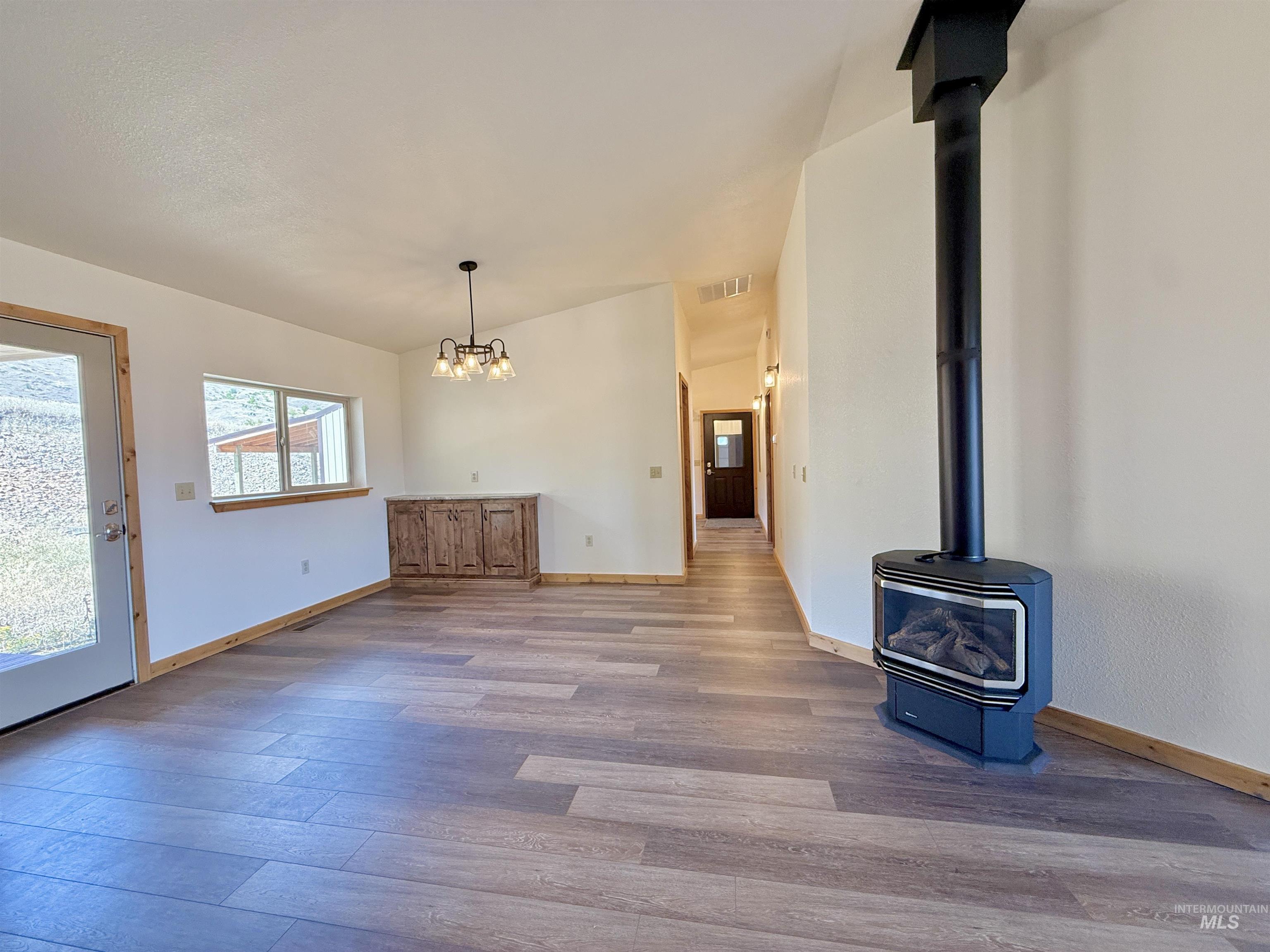 150 Buck Boulevard White Bird, ID 83554 - Photo 6 of 45 Unfurnished living room featuring a wood stove, wood finished floors, and a chandelier