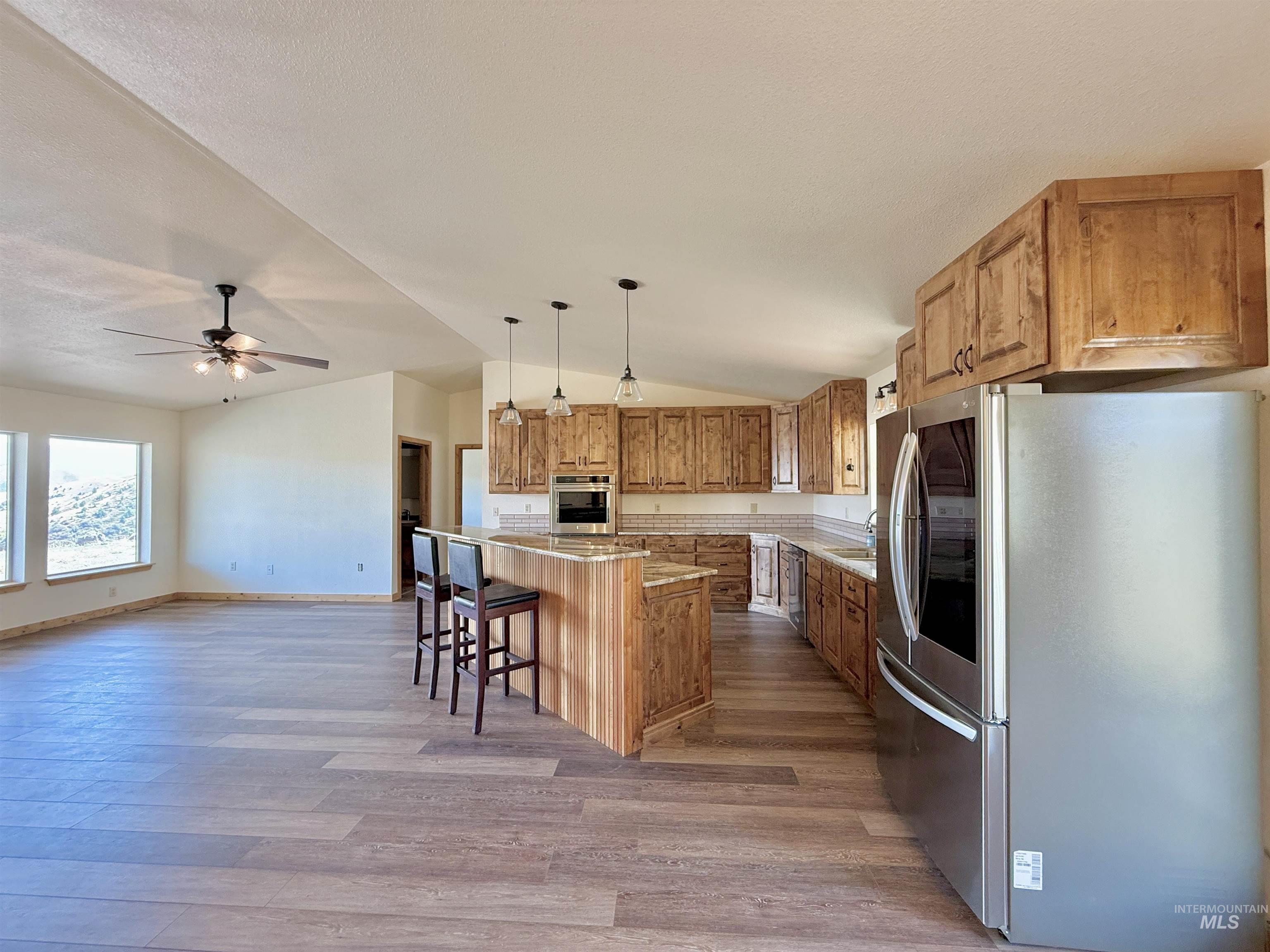 150 Buck Boulevard White Bird, ID 83554 - Photo 7 of 45 Kitchen with appliances with stainless steel finishes, lofted ceiling, light wood-type flooring, a center island, and a breakfast bar