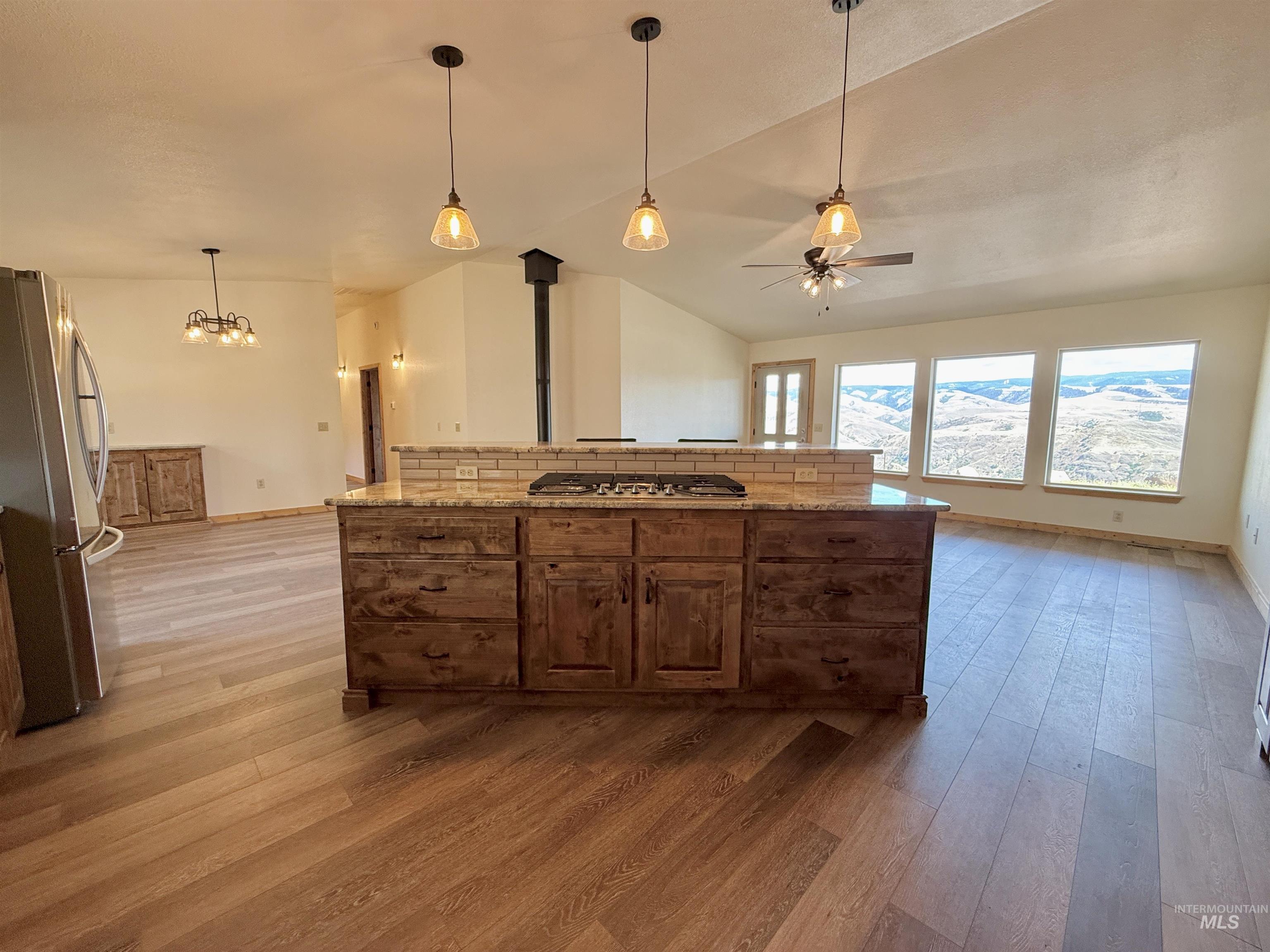 150 Buck Boulevard White Bird, ID 83554 - Photo 9 of 45 Kitchen with lofted ceiling, appliances with stainless steel finishes, light wood-type flooring, decorative backsplash, and light stone counters