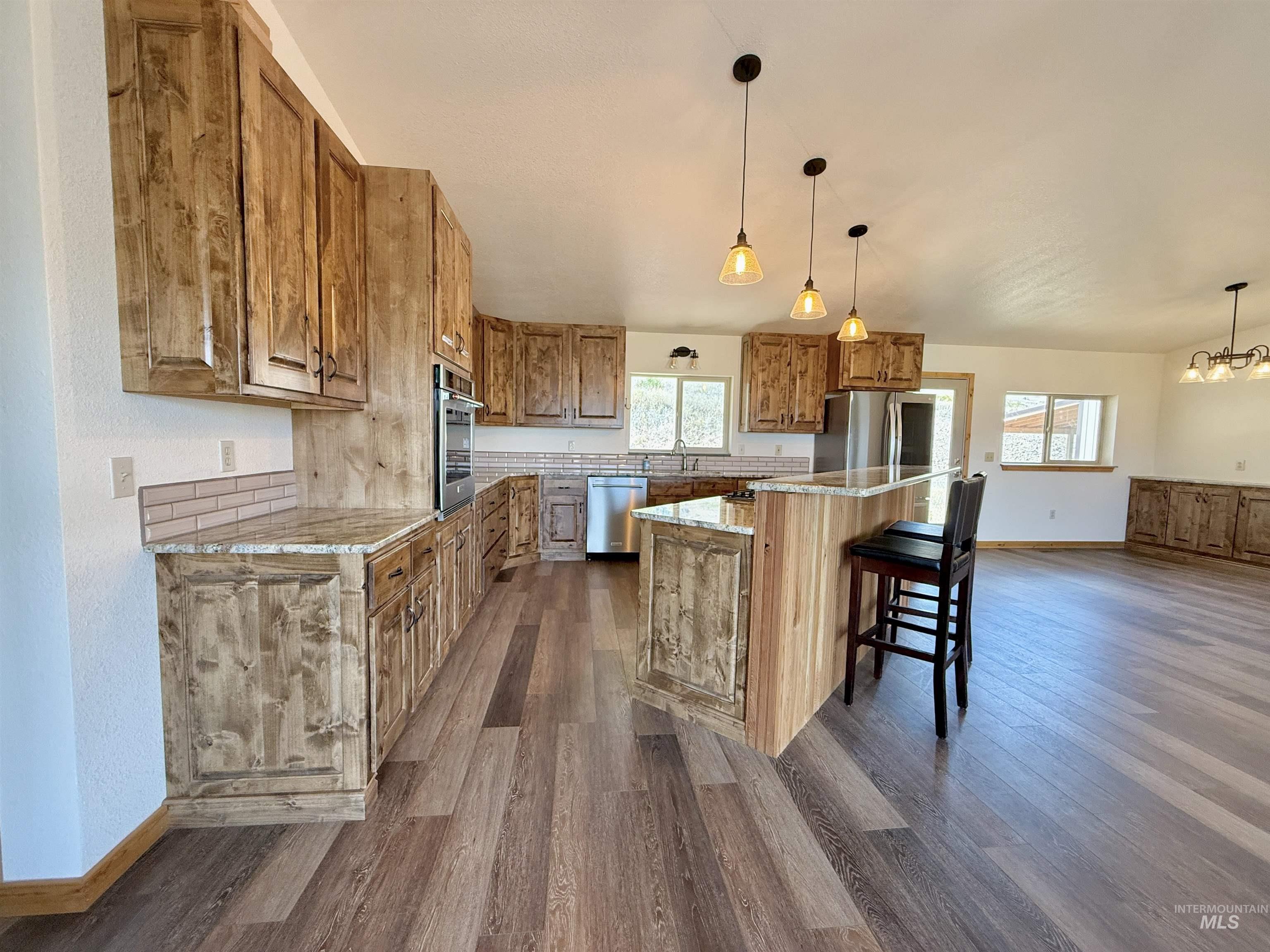 150 Buck Boulevard White Bird, ID 83554 - Photo 10 of 45 Kitchen featuring brown cabinetry, dark wood finished floors, a center island, and healthy amount of natural light