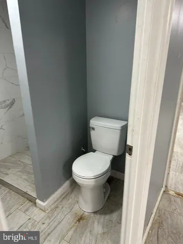 a white toilet sitting next to a shower