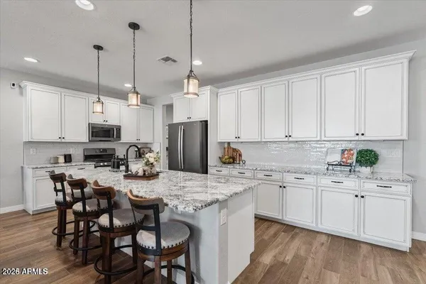 a kitchen with stainless steel appliances kitchen island granite countertop a table chairs microwave and sink