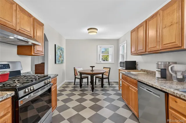 a kitchen with stainless steel appliances granite countertop a stove a sink a dining table and chairs with wooden floor