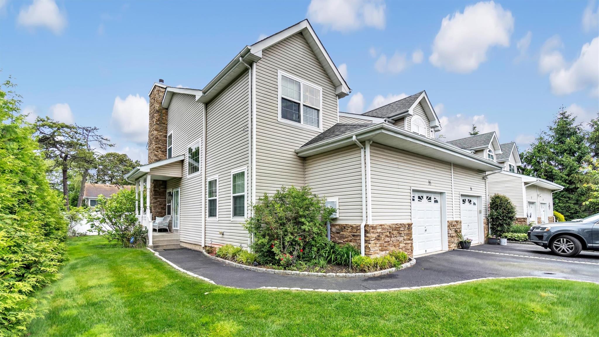 View of home's exterior featuring asphalt driveway, a lawn, stone siding, a chimney, and an attached garage