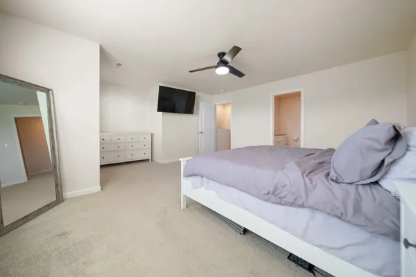 a bedroom with a large bed a flat tv screen and a dresser