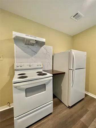 a white refrigerator freezer and a stove sitting inside of a kitchen