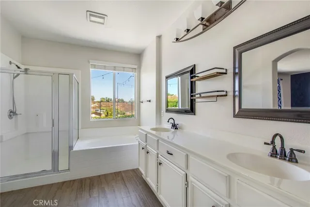a bathroom with a double vanity sink a mirror a window and a bathtub