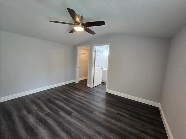 an empty room with wooden floor ceiling fan and window