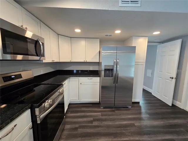 a kitchen with stainless steel appliances kitchen island granite countertop a stove a sink and a microwave