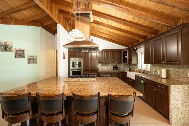 a large kitchen with kitchen island granite countertop a large counter space wooden floor and stainless steel appliances