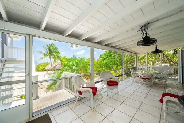 a view of a white house with a yard and palm trees