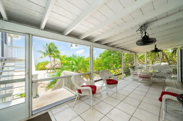 a view of a white house with a yard and palm trees