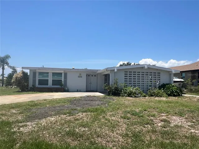 a view of a house with a yard and a large tree