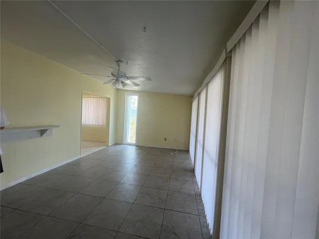 a view of an empty room and window and chandelier fan