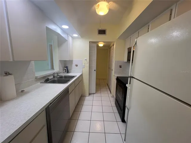 a kitchen with a sink a refrigerator and cabinets