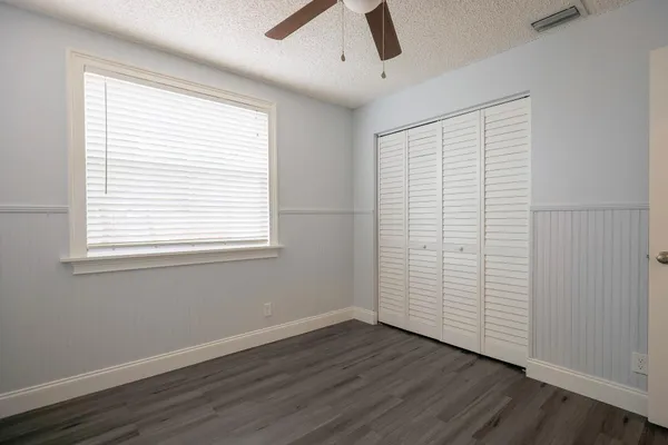 an empty room with wooden floor fan and windows