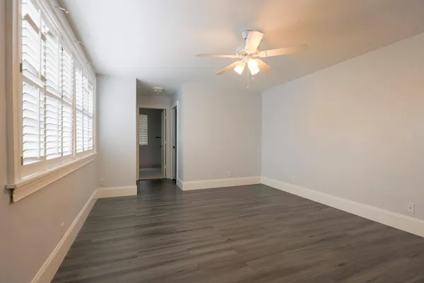 a view of an empty room with wooden floor and a window