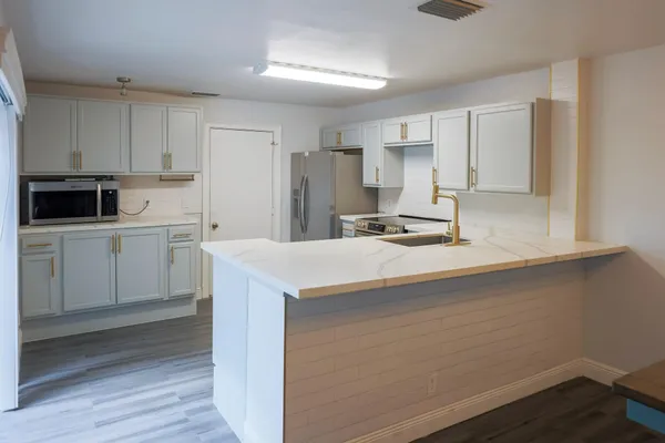a kitchen with a sink a stove a refrigerator and white cabinets