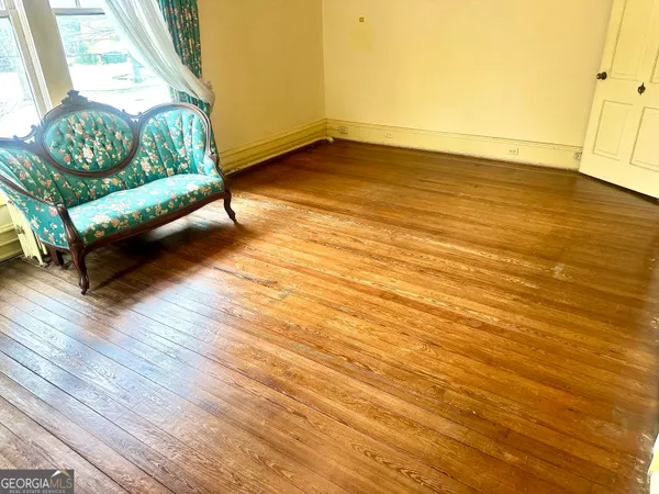 a view of an empty room with a window and hardwood floor