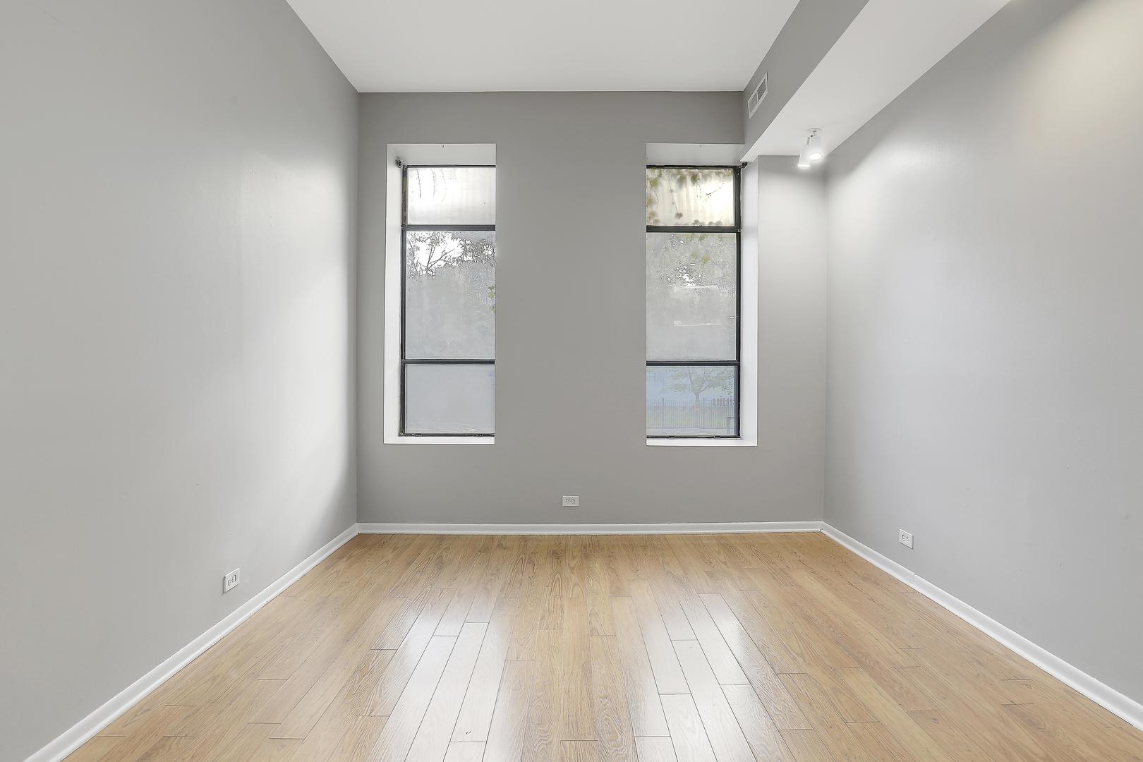 1726 North Sedgwick Street, Unit 1F Chicago, IL 60614 - Photo 3 of 8 an empty room with wooden floor and windows