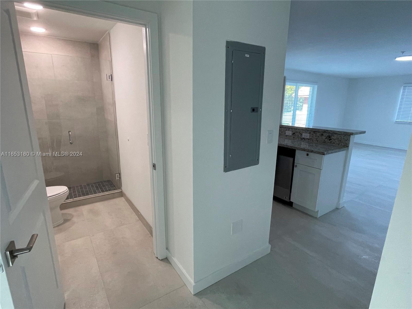 535 Southwest 5th Street, Unit 5 Miami, FL 33130 - Photo 5 of 19 a bathroom with a granite countertop sink a toilet a mirror and vanity