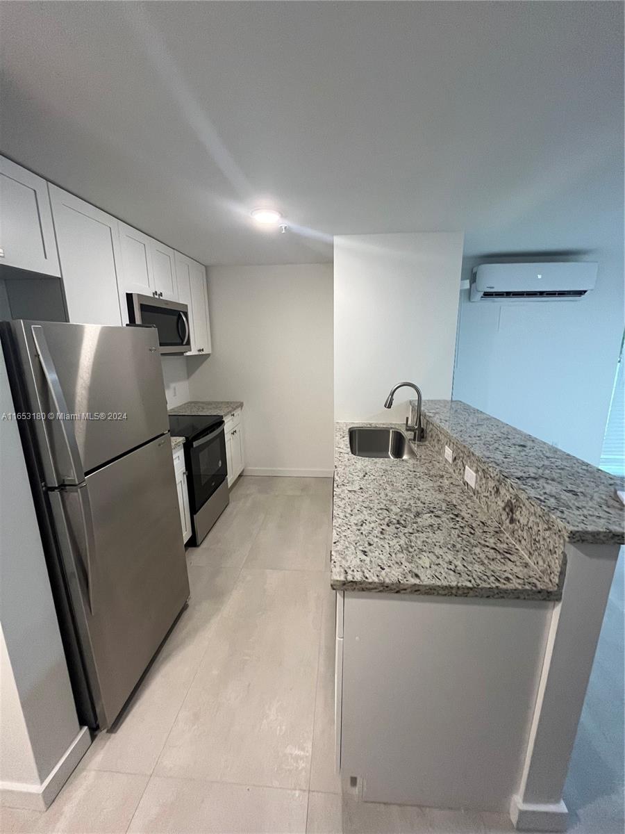 535 Southwest 5th Street, Unit 5 Miami, FL 33130 - Photo 8 of 19 a kitchen with kitchen island a sink a stove and refrigerator