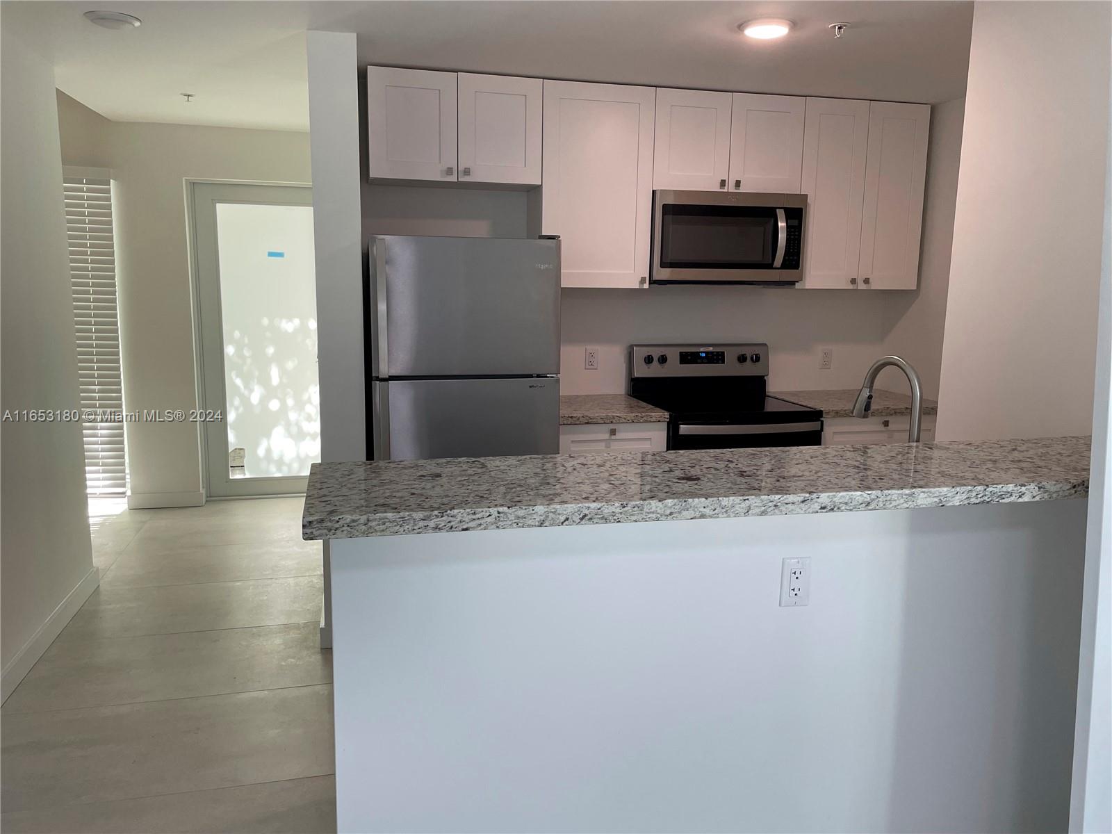 535 Southwest 5th Street, Unit 5 Miami, FL 33130 - Photo 9 of 19 a kitchen with granite countertop a refrigerator a microwave a sink and cabinets