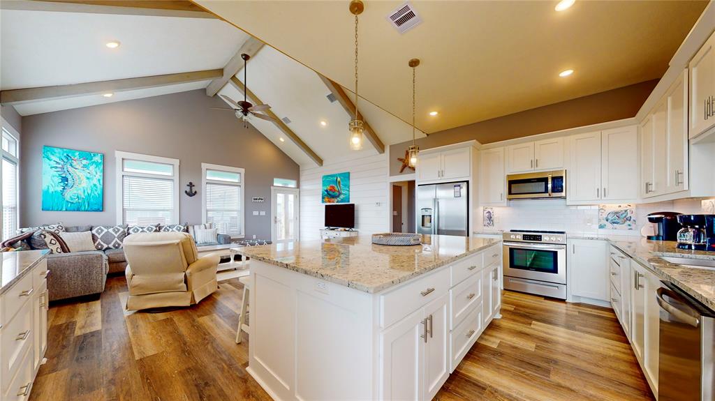 a large white kitchen with stainless steel appliances granite countertop lots of counter space and windows