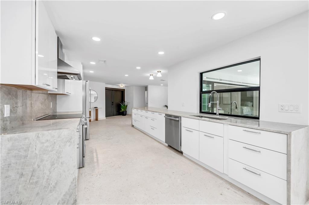 3777 Fountainhead Lane Naples, FL 34103 - Photo 3 of 18 a large white kitchen with kitchen island a sink stainless steel appliances and cabinets