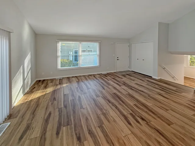 an empty room with wooden floor and windows
