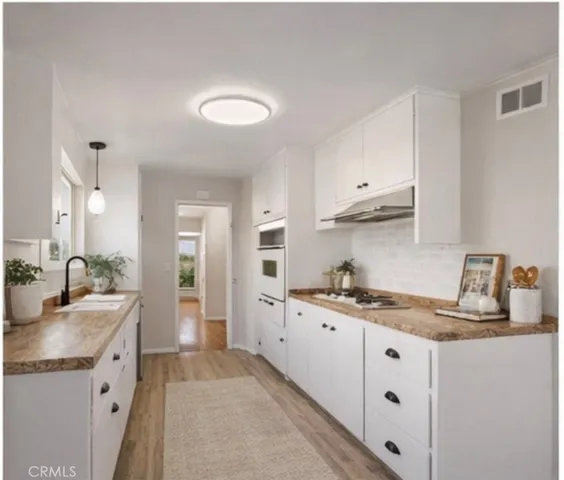 a kitchen with granite countertop a sink stove and cabinets
