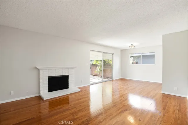 an empty room with wooden floor fireplace and windows