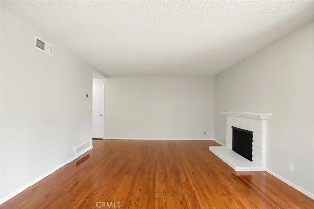 a view of empty room with wooden floor and fireplace